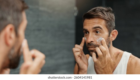 Man performing skincare routine at bathroom mirror